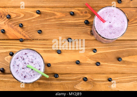 Deux verres de smoothie myrtilles et petits fruits éparpillés sur la table, vue du dessus Banque D'Images