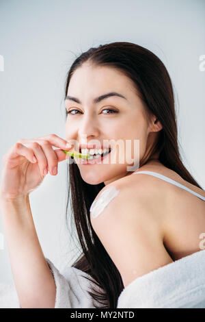 Portrait de jeune femme souriante avec la peau douce de manger une tranche de concombre et looking at camera Banque D'Images