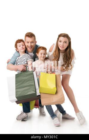 Heureux jeune famille avec deux enfants holding paper bags isolated on white Banque D'Images