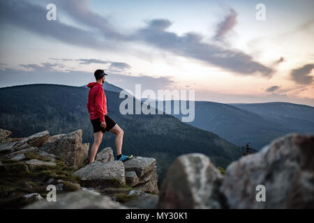 Célébrer le coucher du soleil à l'homme à vue dans les montagnes. Trail Runner, randonneur ou alpiniste atteint haut de la montagne, profiter du paysage d'inspiration sur rocky Banque D'Images