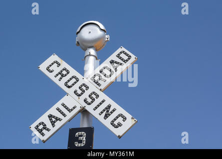 Railroad crossing sign avec petites lumières sur les lettres contre le ciel bleu Banque D'Images