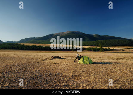 Moto enduro avec tente Camp Voyageur seul steppe paysage en arrière-plan de haute montagne au lever du soleil sur les montagnes de l'Altaï Sibérie Russie Banque D'Images