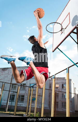 Vue arrière de basket-ball joueur arrivé ballon dans panier pendant le jeu Banque D'Images