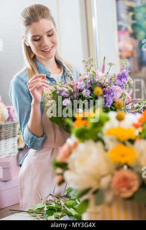 Belle smiling woman in apron holding bouquet et l'arrangement des fleurs dans le magasin de fleurs Banque D'Images