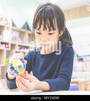 Petite fille asiatique se concentre sur la peinture de son art doll Banque D'Images