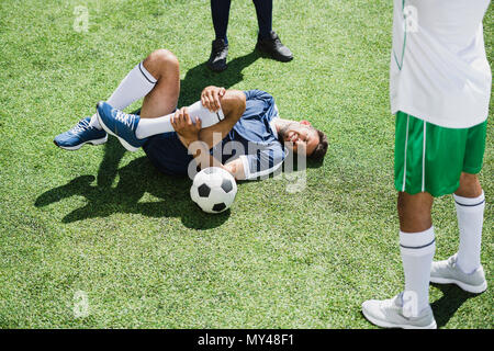 Le joueur de soccer blessés gisant sur terrain de football au cours de match Banque D'Images