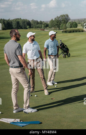 Les jeunes joueurs de golf multiethnique à l'écart en se tenant sur le terrain Banque D'Images