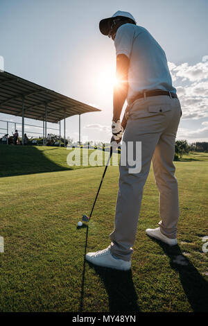 Low angle view of man en cap et lunettes de jouer au golf avec bois et ball Banque D'Images