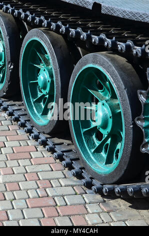 Un véhicule militaire sur chenilles se tient sur un carré de pavés. Photo de chenilles vertes avec des roues en métal que les faire tourner Banque D'Images