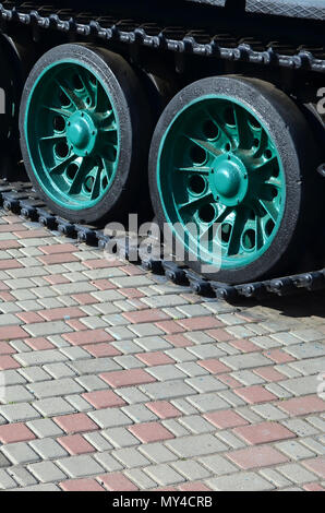 Un véhicule militaire sur chenilles se tient sur un carré de pavés. Photo de chenilles vertes avec des roues en métal que les faire tourner Banque D'Images