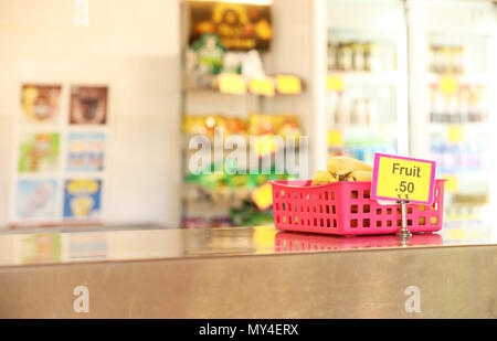 Cantine de l'école tuck shop cafétéria vendant des fruits sains : options pour les étudiants. les bananes dans un bac en acier inoxydable rouge sur le banc en premier plan Banque D'Images