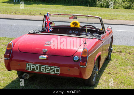 Un vintage MG motor car ou voiture de sport avec un tournesol sur la planche de bord et le toit vers le bas dans le bain de l'été. MG Midget vintage voiture de sport. Banque D'Images