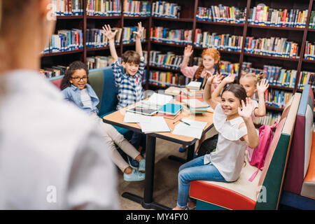 Adorables petits enfants sensibilisation mains in library Banque D'Images