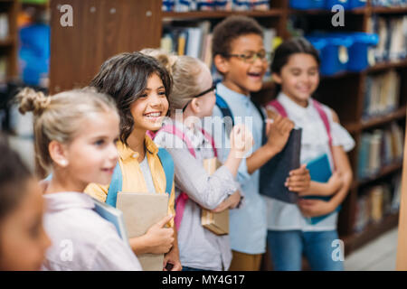 Cute kids en ligne debout dans la bibliothèque avec des livres Banque D'Images