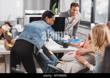 Les gens s'amuser dans office, les femmes autocollants colle sur l'homme Banque D'Images