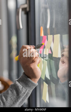 Portrait de l'homme en prenant des notes sur des autocollants fenêtre à Banque D'Images