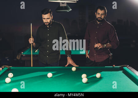 Couple d'hommes debout à côté d'une table de billard avec un verre au bar Banque D'Images