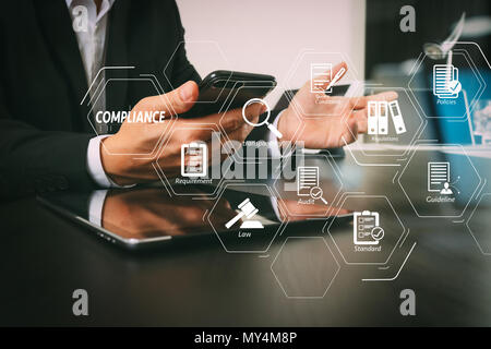 Schéma de la conformité pour les règlements, les lois, les normes, les exigences et l'audit.businessman working with smart phone et l'ordinateur portable et tablette numérique Banque D'Images