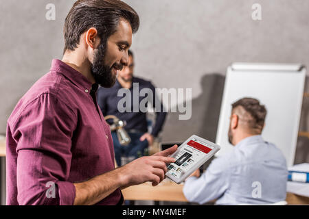 Smiling businessman looking at tablet avec bbc news page Banque D'Images