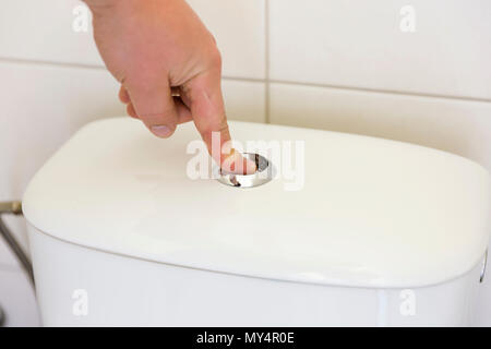 Doigt appuyant sur le bouton et le rinçage des toilettes. Banque D'Images