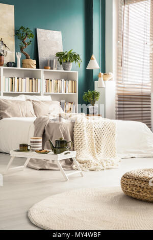 Bac blanc avec pot et tasses debout sur le sol en face d'un lit confortable à l'intérieur chambre à coucher moderne Banque D'Images