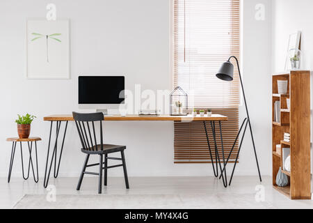 À côté de bureau en bois avec le moniteur de l'ordinateur de bureau à domicile avec l'intérieur de l'affiche. Photo réelle Banque D'Images