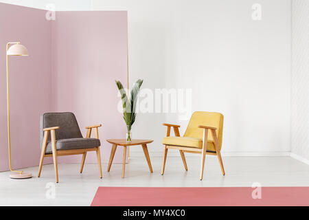 En bout de table en bois avec la plante fraîche en vase en verre debout entre gris et blanc en fauteuils moutarde prix minimal interior Banque D'Images