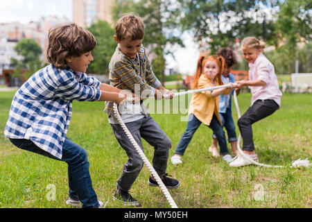 Adorable happy kids jouer remorqueur de la guerre in park Banque D'Images