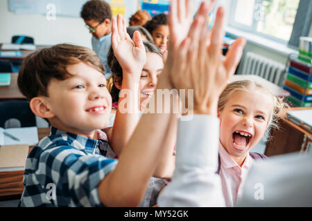 Vue rapprochée d'enfants donnant à l'enseignant-e high five Banque D'Images