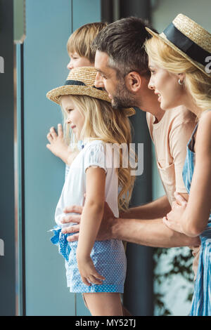 Vue latérale d'happy family looking out window in airport Banque D'Images