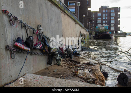 Londres, Angleterre, Royaume-Uni - 14 janvier 2014 : Chaussures trouvées jonchant les rives de la marée de la Tamise sont suspendus le long de la digue de Battersea Riv Banque D'Images