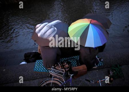 16 mai 2018, l'Allemagne, Erfurt : jeunes assis sous parasols à la Gera river en face de l'Kraemer pont. Le pont est le plus long d'Europe avec des maisons occupées en continu. C'est l'un d'Erfurt. Des centaines de milliers de touristes venus visiter la ville chaque année à cause du pont. Photo : Carsten Koall/dpa Banque D'Images