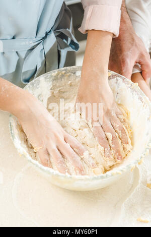 Portrait de femme mains pétrissant la pâte dans le bol sur la table de cuisine à Banque D'Images