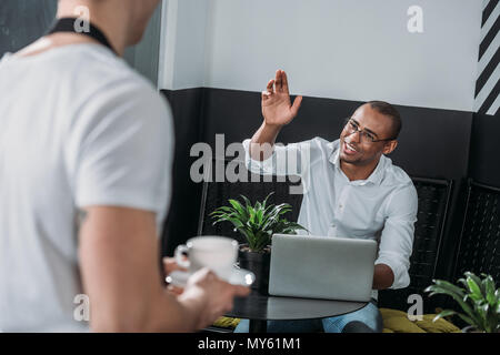 Young african american man waving to waiter avec du café dans la main Banque D'Images