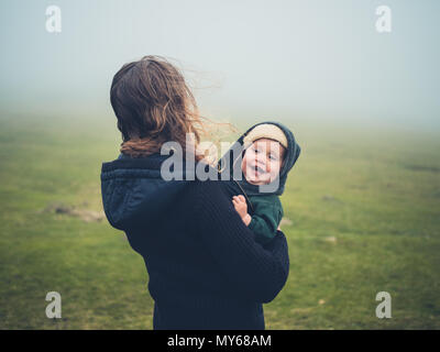 Une jeune mère avec un bébé est debout sur la lande dans le brouillard Banque D'Images