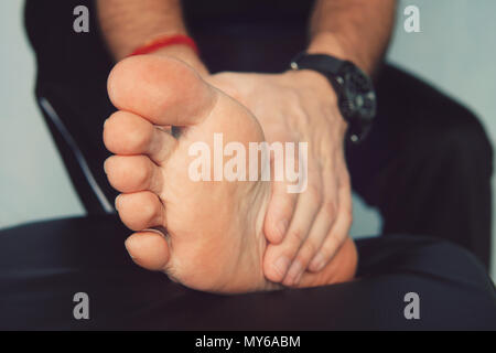 La main de l'homme massée un pied. Avec l'homme et l'inflammation douloureuse la goutte sur son pied autour du gros orteil. Banque D'Images