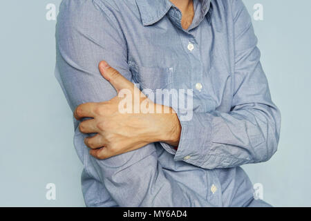 Guy avec chemise en tenant main d'un biceps malades sur fond bleu. La douleur dans mes bras. Mal de biceps. une balle dans le bras. arthrite, arthrose, inflammat Banque D'Images