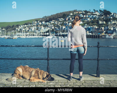 Une jeune femme avec un énorme chien Léonberg est debout près de la rivière dans un petit village Banque D'Images