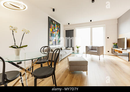 Chaises noir à table avec des fleurs en intérieur appartement spacieux avec canapé et fauteuil. Photo réelle Banque D'Images