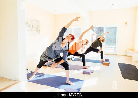 Trois femmes qui pratiquent l'angle de côté sur une jambe, (parsvakonasana) yoga pose in yoga studio Banque D'Images