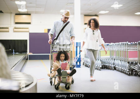 Famille avec fille sur le chariot à bagages dans l'aéroport Banque D'Images