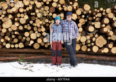 Portrait de père et fils, en face de pile de grumes Banque D'Images
