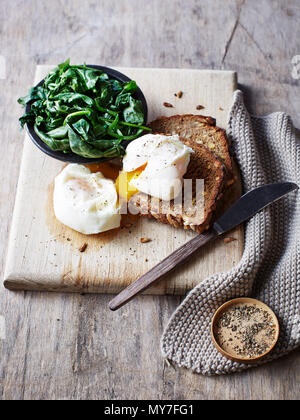 Nature morte aux épinards et oeuf poché sur toast sur planche, overhead view Banque D'Images