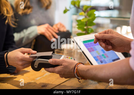 La clientèle féminine en boutique, le paiement des biens à l'aide de carte de crédit sur la machine de paiement sans contact, mid section, close-up Banque D'Images