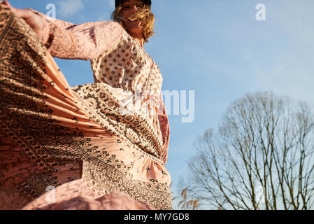 Style hippie woman dancing against blue sky, low angle view Banque D'Images