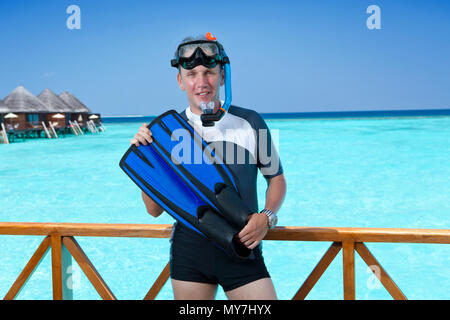 L'homme sportif avec palmes, masque et tube sur une terrasse d'une maison sur la mer. Maldives Banque D'Images