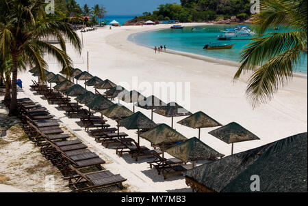 Belle maison de plage paysage avec des rangées de transats en bois et parasols aux toits de chaume. Les touristes à marcher le long de sable blanc poudreux. Banque D'Images