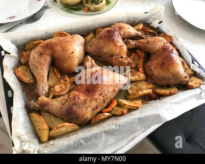 Des cuisses de poulet épicé grillé avec des pommes de terre sur un plat à four. L'alimentation biologique. Banque D'Images