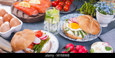 Du pain avec du fromage, l'oeuf et l'asperge, un autre pain avec le saumon et les asperges.. Alimentation saine. Délicieux petit-déjeuner. Fond gris. Bannière, copy space Banque D'Images