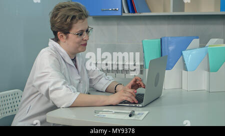 Femme médecin concentré dans les verres de la saisie sur ordinateur portable dans son bureau Banque D'Images